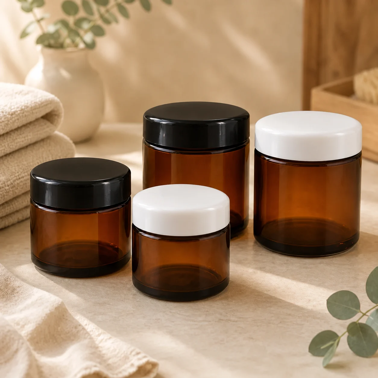 Four amber lotion jars in two sizes, with black and white screw lids